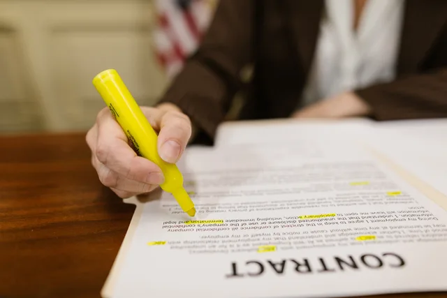 A close-up of a hand highlighting a contract, emphasizing important legal terms. Granska ett tjänsteföretags uppgifter före köp