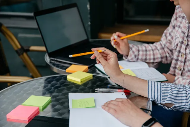 Two people collaborating, using pencils and sticky notes at a glass table. Hitta rätt tjänstekategori för ditt behov